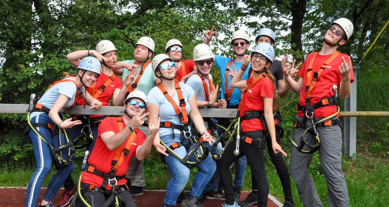 Eine Gruppe Jugendliche mit Kletterausrüstung lacht in die Kamera.