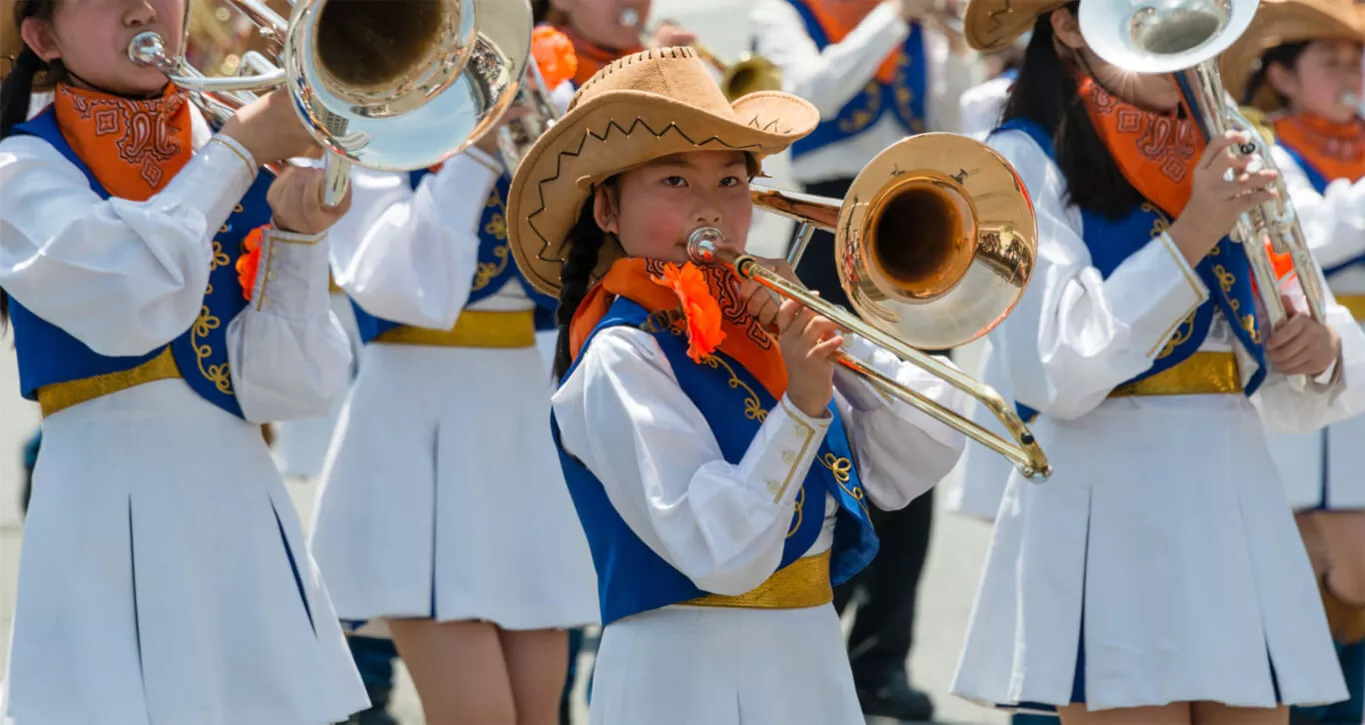Junge Posaunistinnen in einheitlicher traditioneller Uniform marschieren.